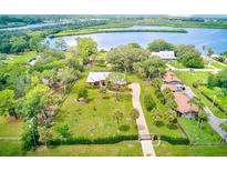 Aerial view of a waterfront home with a large yard, lush landscaping, and a paved driveway at 2307 7Th Sw St, Ruskin, FL 33570