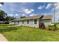 Newly built single-story home with gray siding, stone accents, and landscaped yard at 911 8Th Sw Ave, Largo, FL 33770