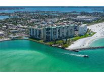 Aerial view of beachfront condo building with ocean and city views, highlighting its prime coastal location at 7100 Sunset Way # 405, St Pete Beach, FL 33706