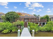 Waterfront home featuring a private wooden dock, screened lanai, and lush tropical landscaping at 1233 Acappella Ln, Apollo Beach, FL 33572