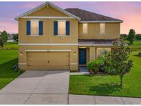 Two-story house with beige exterior, blue shutters, and a two-car garage at 35716 Hillbrook Ave, Zephyrhills, FL 33541