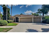 Beige house with three car garage and palm trees at 14302 King Tom Pl, Ruskin, FL 33573