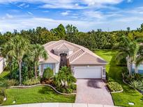 Single-story home with tile roof, palm trees, and landscaped yard at 5014 Ruby Flats Dr, Wimauma, FL 33598