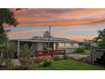 Backyard with wooden deck, hot tub, and string lights at sunset at 2419 Roxbury Cir, North Port, FL 34287