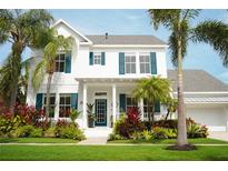 Beautiful two-story home featuring a lush lawn, mature palm trees, and teal window shutters at 415 Islebay Dr, Apollo Beach, FL 33572
