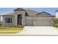Charming single-story home with stone accents, a well-manicured lawn, and an attached two-car garage at 12977 Long Valley Cir, Spring Hill, FL 34609