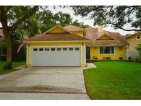 Yellow house with a two-car garage and landscaped lawn at 7519 Harbor View Way, Seminole, FL 33776