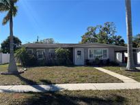 Charming single-story home with a well-manicured lawn, mature palm trees, and a cozy carport at 15536 Bristol E Cir, Clearwater, FL 33764