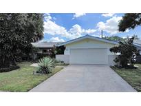 Ranch-style home with a large driveway and well-maintained lawn at 1385 Embassy Dr, Clearwater, FL 33764