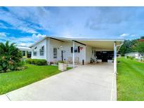 White single-wide manufactured home with carport and landscaped lawn at 3843 Damian Dr, Zephyrhills, FL 33541
