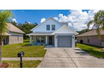 Charming two-story home with a gray garage, well-kept lawn and landscaping under blue skies at 10209 Summerview Cir, Riverview, FL 33578