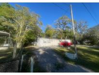 Exterior view of home with gravel driveway and red truck parked in front at 10542 Helena St, New Port Richey, FL 34654