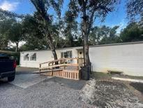 This property features a ramp leading to the home's entrance, nestled amidst lush trees and a spacious front yard at 10542 Helena St, New Port Richey, FL 34654