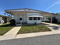 Charming single-story home featuring a covered parking area and a well-maintained front lawn at 2331 Belleair Rd # Lot 237, Clearwater, FL 33764