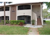 Two-story condo building with a walkway and landscaping at 2983 Bonaventure Cir # 103, Palm Harbor, FL 34684