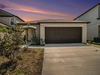 Charming house with a brown garage door and landscaping at 16762 Delia St, Wimauma, FL 33598