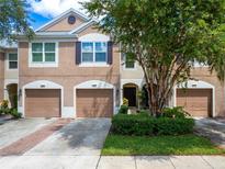 Tan three-unit townhouse with garages and landscaping at 26607 Chimney Spire Ln, Wesley Chapel, FL 33544