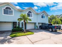 Light blue three-unit building with attached garages and a palm tree at 639 Garland Cir, Indian Rocks Beach, FL 33785