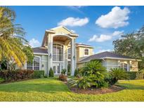 Beautiful two-story home with manicured lawn, large windows, and a grand arched entryway, creating an inviting facade at 1935 Lago Vista Blvd, Palm Harbor, FL 34685