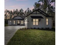 White modern farmhouse exterior with a three-car garage and landscaped lawn at 4817 Majestic Hills Loop, Brooksville, FL 34601