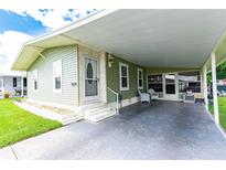 Light green mobile home with carport and landscaping at 36839 Tara Ave, Zephyrhills, FL 33542