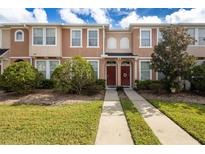 Two story townhome with red door and landscaped lawn at 6950 Towering Spruce Dr, Riverview, FL 33578
