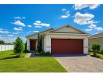 Charming single-story home with a well-maintained lawn, paver driveway, and a lovely red two-car garage door at 11883 Brighton Knoll Loop, Riverview, FL 33579