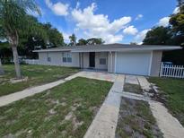 Beige single story home with a white garage door and landscaped yard at 6677 Treehaven Dr, Spring Hill, FL 34606