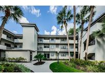 Charming condo building with multiple stories, balconies, beautiful landscaping, and tropical palm trees at 2650 Countryside Blvd # F110, Clearwater, FL 33761