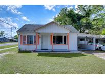 Charming single-story home with a well-manicured lawn and carport, freshly painted white exterior with coral trim at 5829 12Th St, Zephyrhills, FL 33542