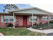 Brick ranch house with covered porch, red door, and landscaping at 1500 85Th N Ave, St Petersburg, FL 33702