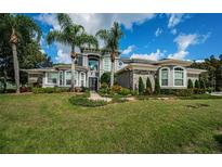 Stunning two-story home boasting stone accents, lush landscaping, and towering palm trees at 180 Keystone Palms Blvd, Tarpon Springs, FL 34688