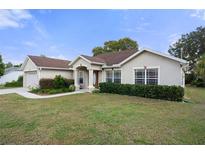 Single-story home with a landscaped lawn and attached garage at 12161 Cavern Rd, Spring Hill, FL 34609