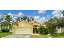 Cute yellow house with a two-car garage and well-manicured lawn at 1122 Vinetree Dr, Brandon, FL 33510