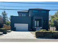Contemporary new construction home featuring a two-car garage and dark exterior paint at 4716 W Euclid Ave, Tampa, FL 33629