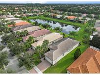 Beautiful aerial view of homes surrounding a tranquil pond in a lush, green community at 15911 Cobble Mill Dr, Wimauma, FL 33598