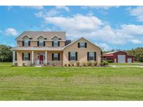 Two-story house with a red door and barn at 8703 Alafia Hills Dr, Plant City, FL 33567