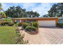 Ranch-style house with orange brick exterior, a white garage door, and landscaped yard at 2505 E 19Th Ave, Tampa, FL 33605