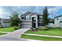 Two-story house with gray siding, stone accents, and a three-car garage at 19065 Malinche Loop, Spring Hill, FL 34610