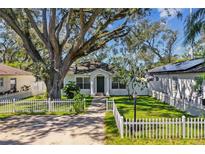 Charming bungalow with a green door, white picket fence, and large oak tree at 6824 N Sterling Ave, Tampa, FL 33614