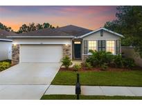 Charming single-Gathering home featuring a two-car garage, stone accents and a beautifully landscaped front yard at 11892 Frost Aster Dr, Riverview, FL 33579