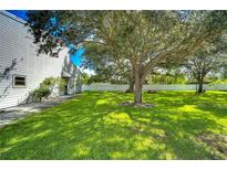 Spacious backyard with lush grass, large tree, and a white fence at 6320 92Nd N Pl # 2601, Pinellas Park, FL 33782