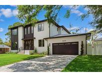 Two-story home with modern architecture, dark trim, manicured lawn and a paved driveway leading to an attached garage at 4625 W El Prado Blvd, Tampa, FL 33629