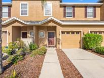 Inviting two-story townhome with a well-manicured lawn, charming facade, and attached garage at 12820 Belvedere Song Way, Riverview, FL 33578