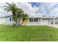 Light blue house with yellow door and palm trees at 5309 Riddle Rd, Holiday, FL 34690