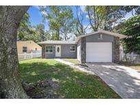 Newly renovated home with gray exterior, white garage door, and landscaped lawn at 7694 62Nd N St, Pinellas Park, FL 33781