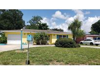 Bright yellow house with a neatly landscaped lawn and driveway at 2392 Indigo Dr, Clearwater, FL 33763