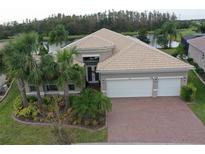 Two-story home with tile roof, three-car garage, and landscaped yard at 16015 Cape Coral Dr, Wimauma, FL 33598