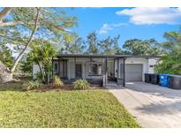 Front exterior of a single-story home with attached garage, screened porch, and landscaped yard at 4519 Venetian Ne Blvd, St Petersburg, FL 33703