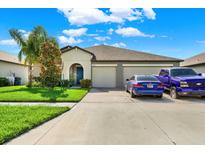 Two-car garage home with a landscaped lawn and driveway at 13573 Willow Bluestar Loop, Riverview, FL 33579